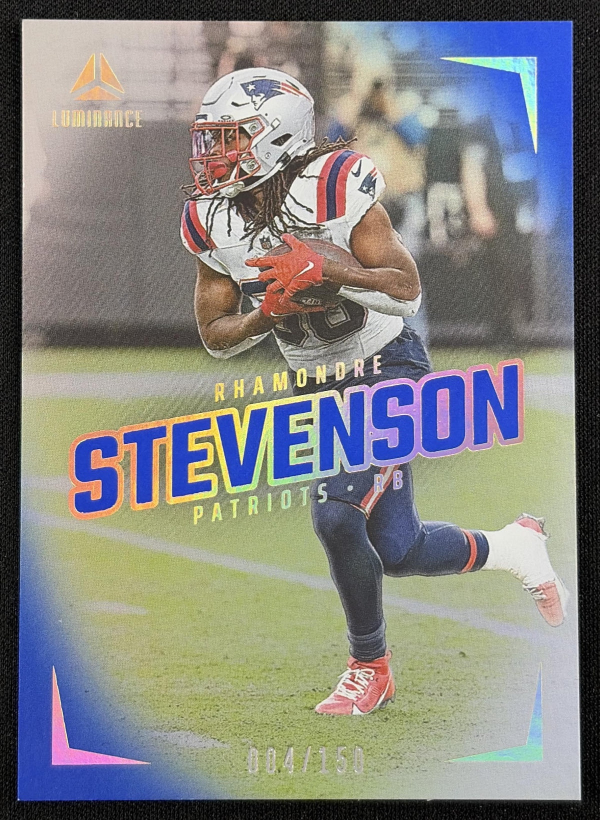 Front of Rhamondre Stevenson 2024 Panini Luminance Blue /150 Patriots sports trading card